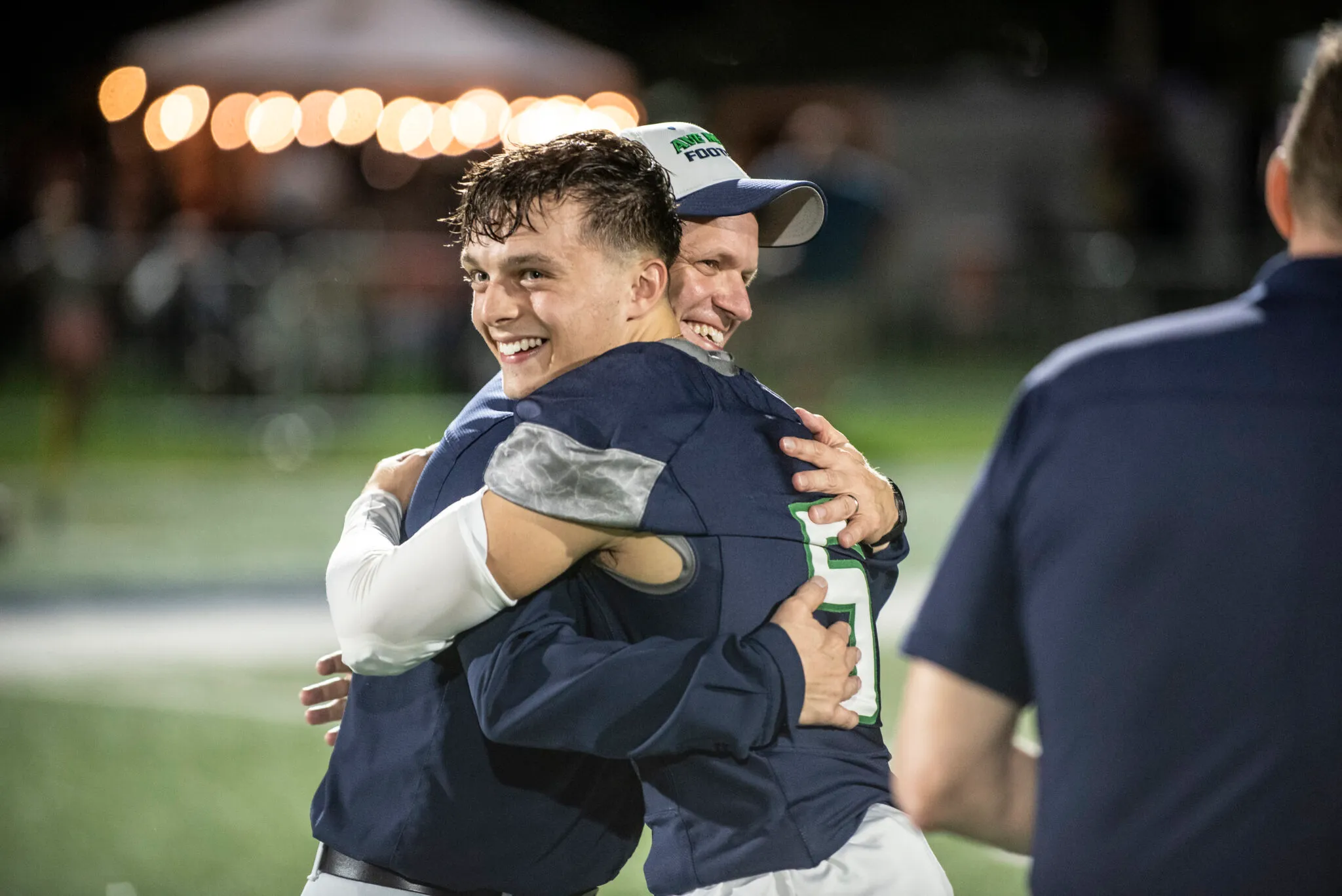 A Gyrenes football player embracing his coach on the field after a night game