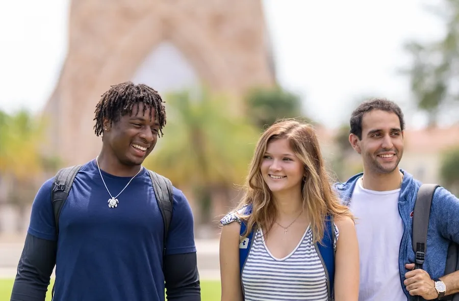 Three Ave Maria University students walking together in front of the Ave Maria Oratory